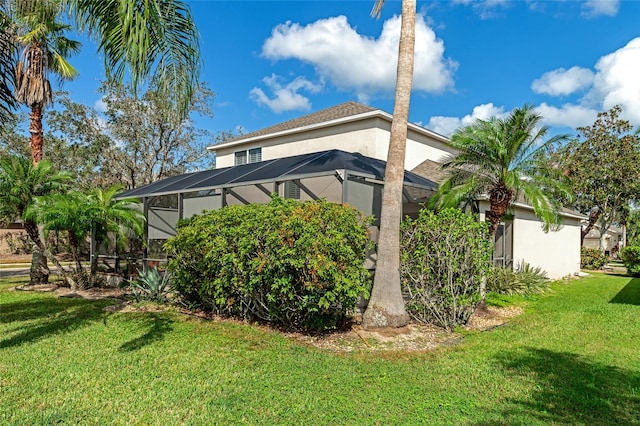 view of side of home featuring a lawn and glass enclosure