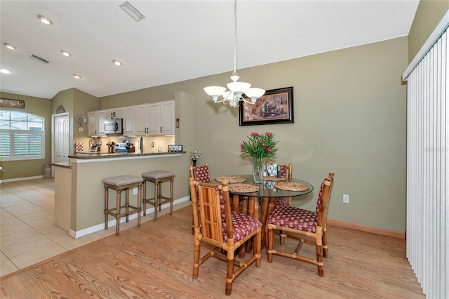 dining room featuring light wood-type flooring and an inviting chandelier