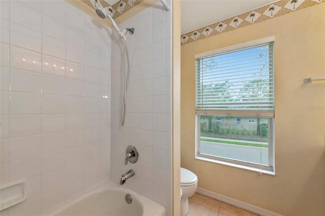 bathroom featuring tile patterned flooring, toilet, and tiled shower / bath combo