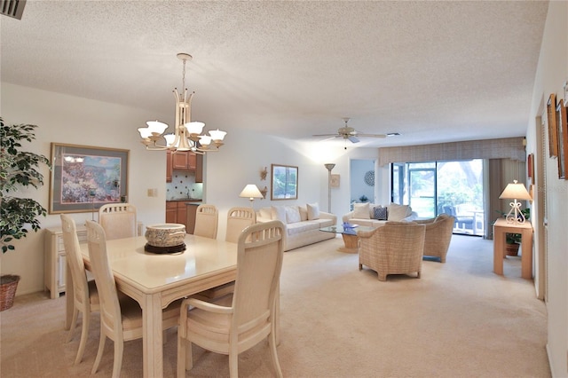 carpeted dining space with ceiling fan with notable chandelier and a textured ceiling