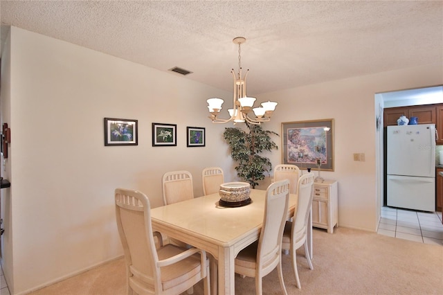 dining space with light colored carpet, a textured ceiling, and a chandelier