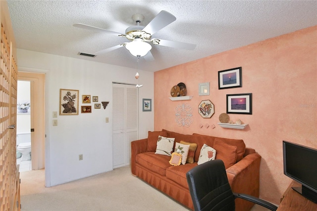 carpeted living room featuring ceiling fan and a textured ceiling