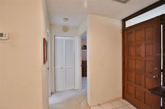 carpeted foyer entrance with a textured ceiling