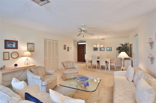 carpeted living room featuring a textured ceiling and ceiling fan with notable chandelier