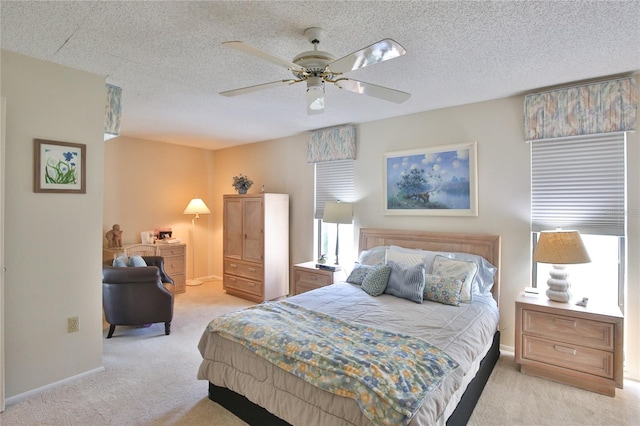 bedroom with a textured ceiling, light colored carpet, and ceiling fan