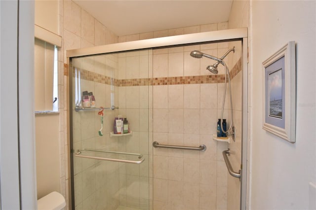 bathroom featuring toilet and a shower with shower door