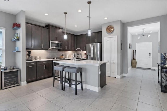 kitchen featuring a chandelier, pendant lighting, dark brown cabinets, a center island with sink, and appliances with stainless steel finishes