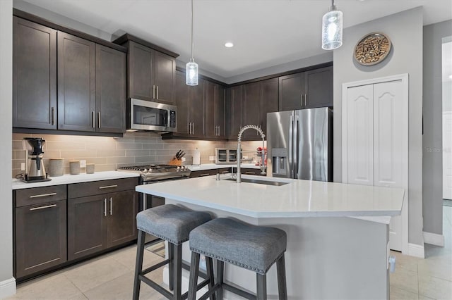 kitchen with pendant lighting, dark brown cabinets, a kitchen island with sink, and appliances with stainless steel finishes