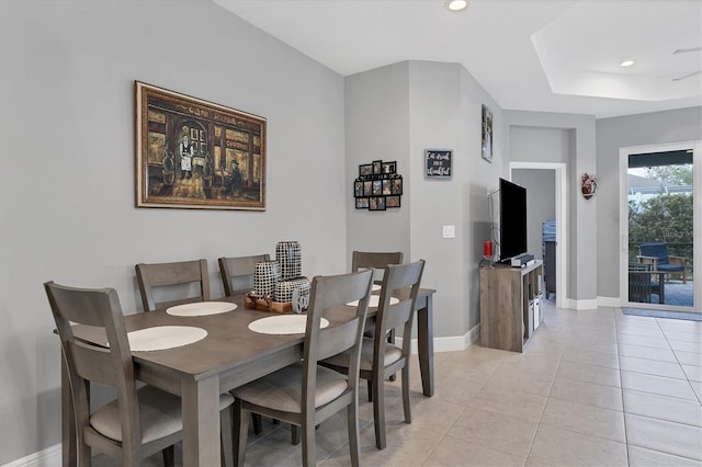 dining area with light tile patterned floors and a raised ceiling