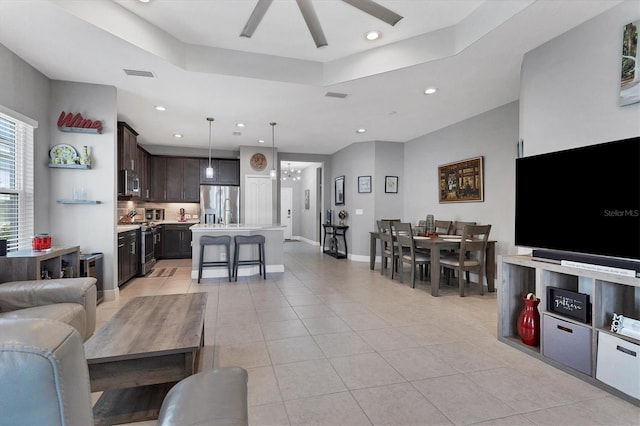 tiled living room featuring ceiling fan and a raised ceiling