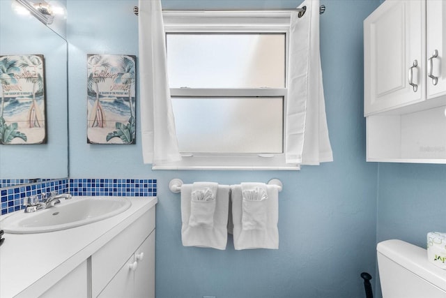 bathroom with decorative backsplash, vanity, and toilet