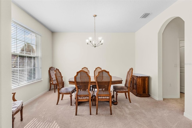 carpeted dining room featuring an inviting chandelier