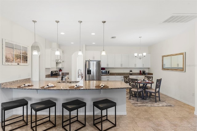 kitchen with white cabinets, a breakfast bar, pendant lighting, and stainless steel appliances