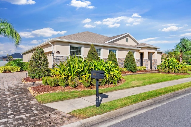 view of front of property with a front lawn, stone siding, an attached garage, and stucco siding