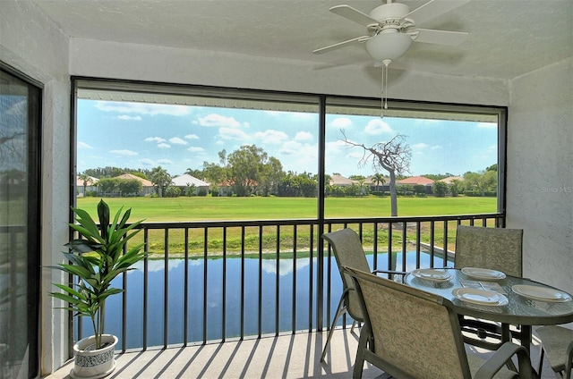 sunroom / solarium featuring a water view and ceiling fan