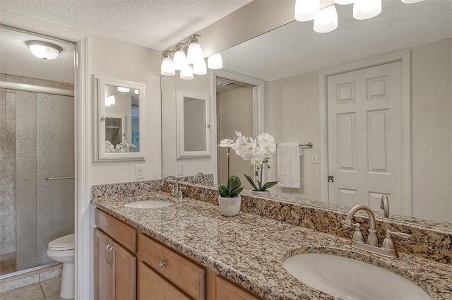 bathroom with a textured ceiling, vanity, a shower with shower door, tile patterned floors, and toilet