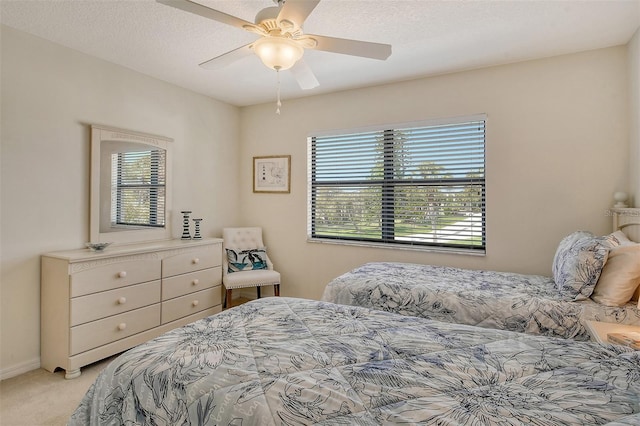 bedroom featuring a textured ceiling, light colored carpet, and ceiling fan