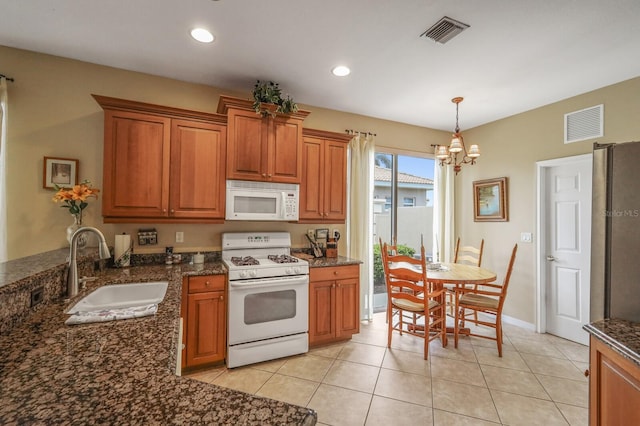 kitchen featuring white appliances, sink, hanging light fixtures, light tile patterned floors, and an inviting chandelier