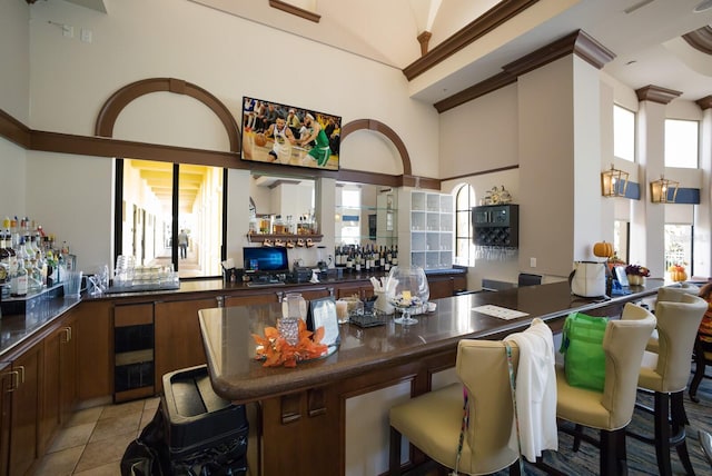 kitchen with a high ceiling, a breakfast bar, and light tile patterned floors