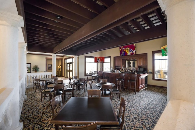 dining room featuring plenty of natural light, beam ceiling, ornate columns, and carpet