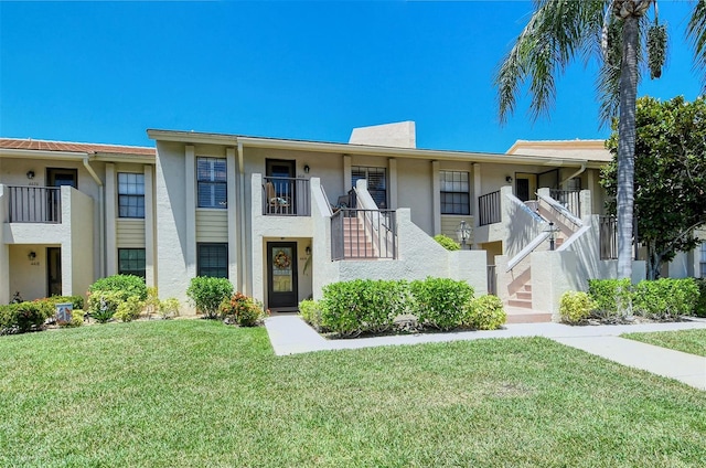 view of property with a front lawn and a balcony