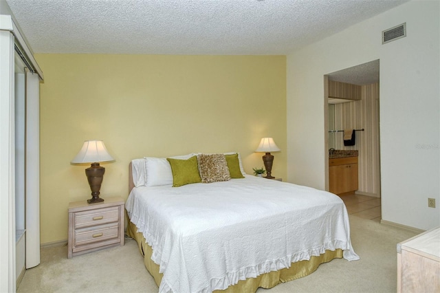 carpeted bedroom featuring ensuite bath, a textured ceiling, and a closet