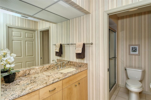 bathroom featuring vanity, a shower with shower door, tile patterned flooring, and toilet