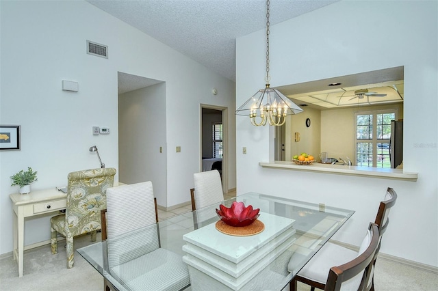 dining space with ceiling fan with notable chandelier, a textured ceiling, high vaulted ceiling, and light colored carpet