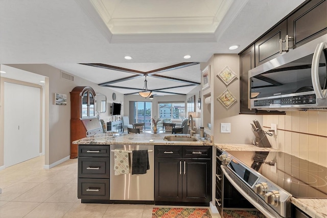 kitchen with light stone counters, sink, a tray ceiling, and appliances with stainless steel finishes