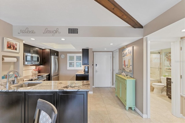 kitchen with sink, green cabinetry, light tile patterned floors, kitchen peninsula, and stainless steel appliances