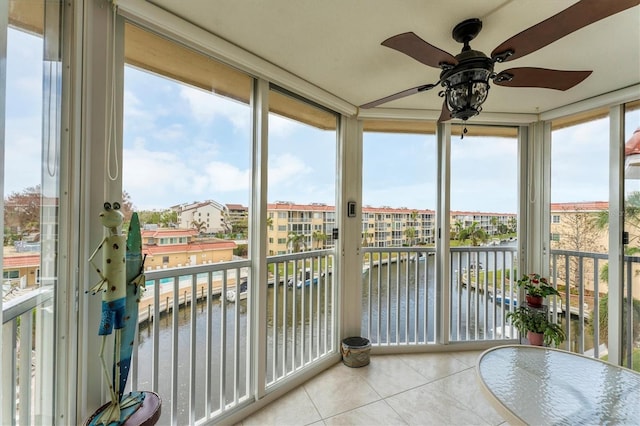 sunroom / solarium featuring a water view and ceiling fan