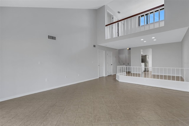 unfurnished living room featuring light tile patterned floors and a high ceiling