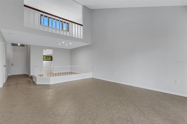 tiled spare room featuring a high ceiling