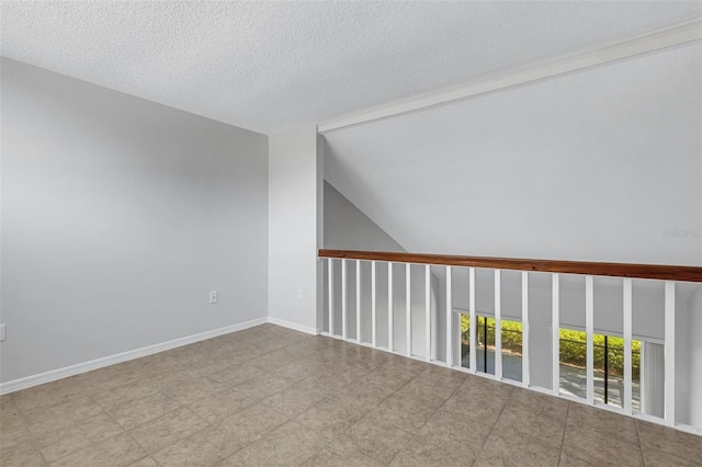 unfurnished room featuring vaulted ceiling and a textured ceiling