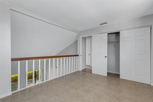 unfurnished bedroom with lofted ceiling, a textured ceiling, a closet, and access to outside