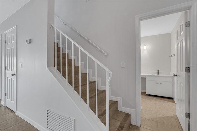 stairs featuring tile patterned floors and sink