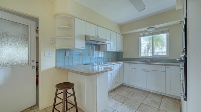 kitchen with white cabinets, a kitchen bar, decorative backsplash, and sink