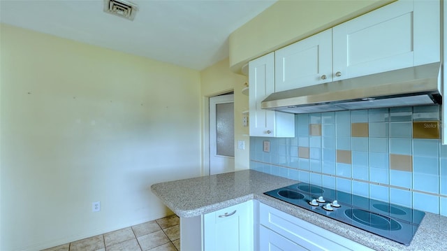 kitchen with white electric cooktop, decorative backsplash, kitchen peninsula, light tile patterned flooring, and white cabinetry