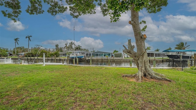 view of property's community with a water view, a lawn, and a boat dock