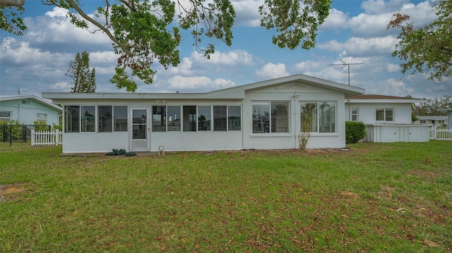 rear view of property with a sunroom and a yard