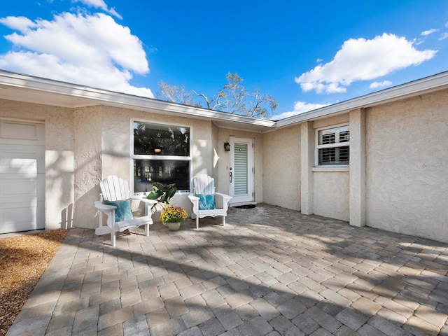 view of exterior entry featuring a patio area and a garage