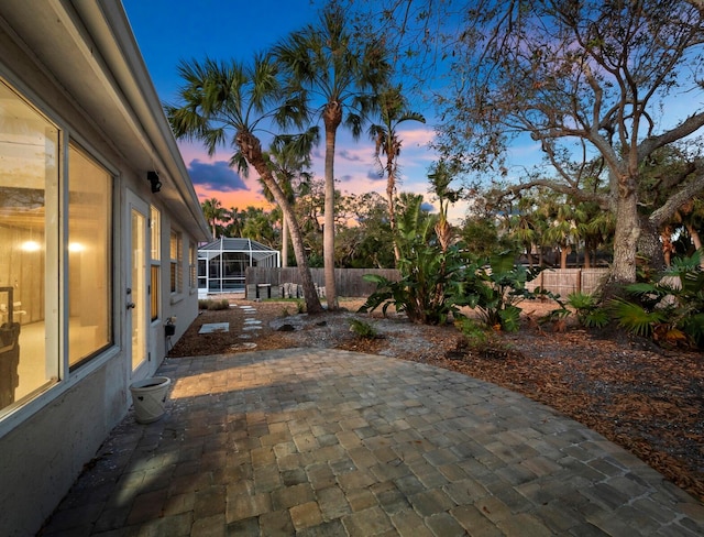 patio terrace at dusk featuring glass enclosure