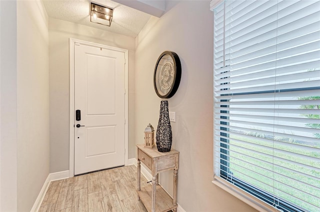 doorway featuring light hardwood / wood-style flooring and a textured ceiling