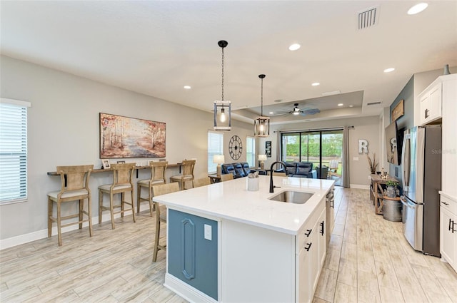 kitchen with sink, an island with sink, white cabinetry, appliances with stainless steel finishes, and decorative light fixtures