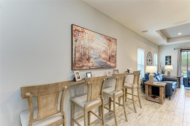 dining room featuring light hardwood / wood-style flooring and a tray ceiling