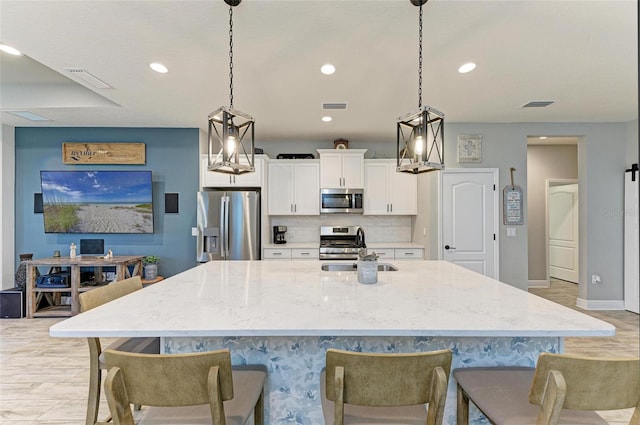 kitchen featuring white cabinetry, sink, appliances with stainless steel finishes, backsplash, and hanging light fixtures