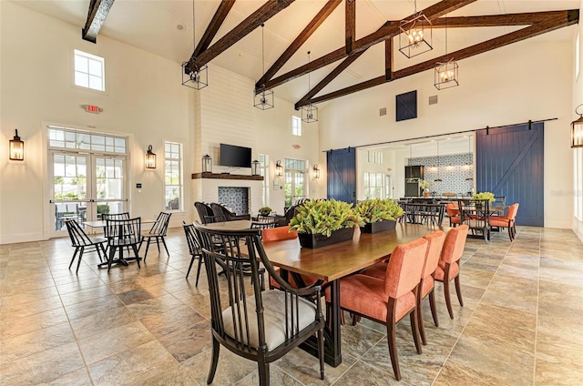 dining area with beamed ceiling, high vaulted ceiling, a fireplace, a barn door, and french doors