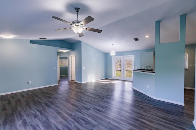 unfurnished living room featuring ceiling fan with notable chandelier, dark hardwood / wood-style flooring, french doors, and vaulted ceiling