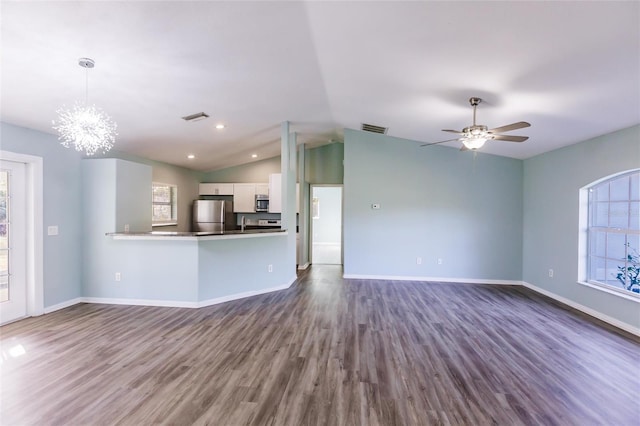 unfurnished living room with ceiling fan with notable chandelier, dark hardwood / wood-style flooring, and lofted ceiling