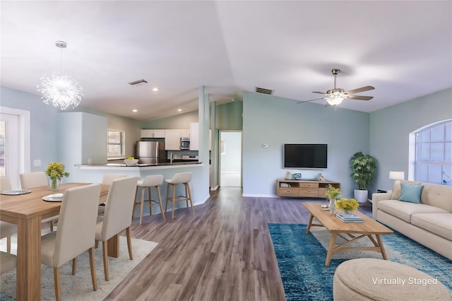 living room with hardwood / wood-style flooring, lofted ceiling, and ceiling fan with notable chandelier